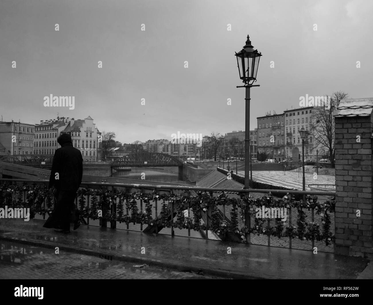 Black and White Photos of Tumski Bridge or Lovers Bridge with Love Locks on it in winter and light snow and Priest walking Stock Photo