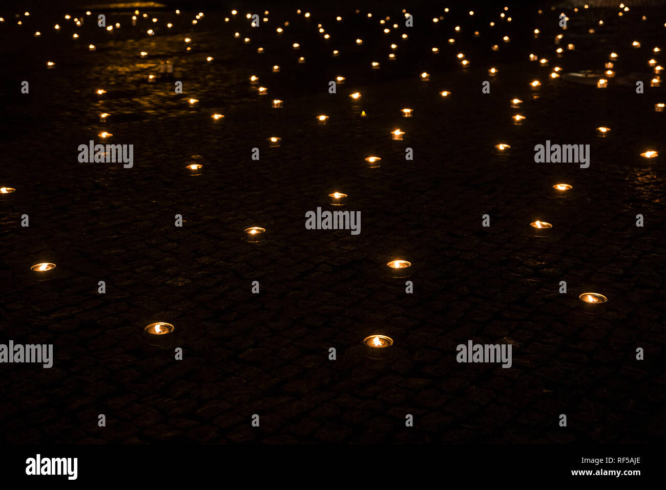 A lot of lit outdoor candles(also known as pitch torch or a garden candle), a lot of out of focus candles burning on the background at night. Stock Photo