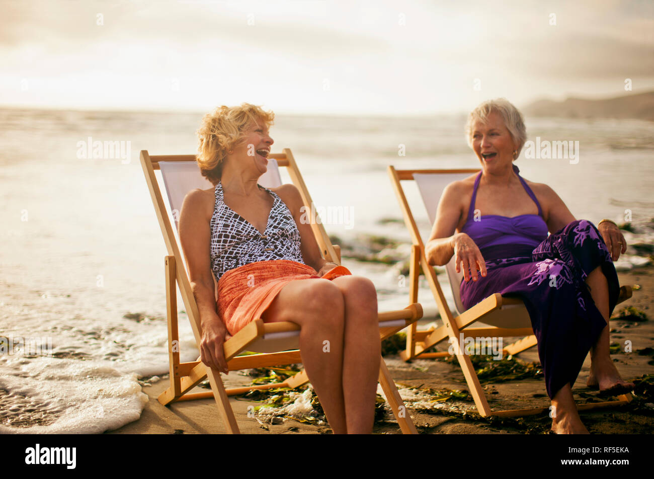 Two happy mature women relaxing in deck chairs on the beach Stock Photo ...