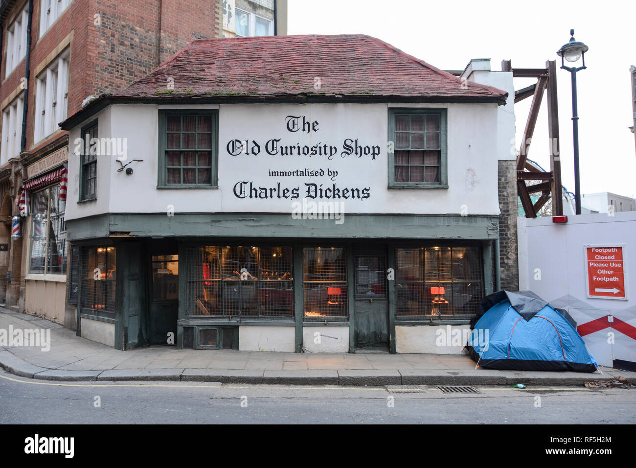 A rough sleeper's tent pitched next to LSE construction works and the famous Old Curiosity Shop on Portsmouth Street, London, WC2, UK Stock Photo