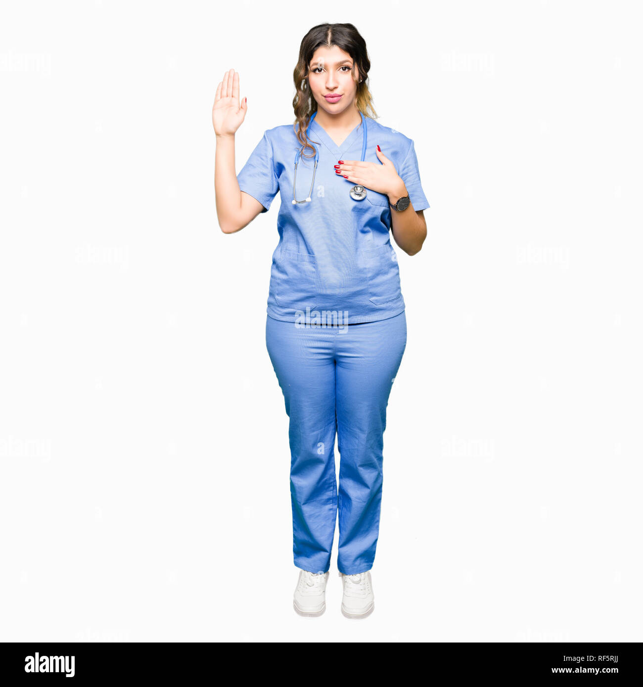 Young adult doctor woman wearing medical uniform Swearing with hand on chest and open palm, making a loyalty promise oath Stock Photo