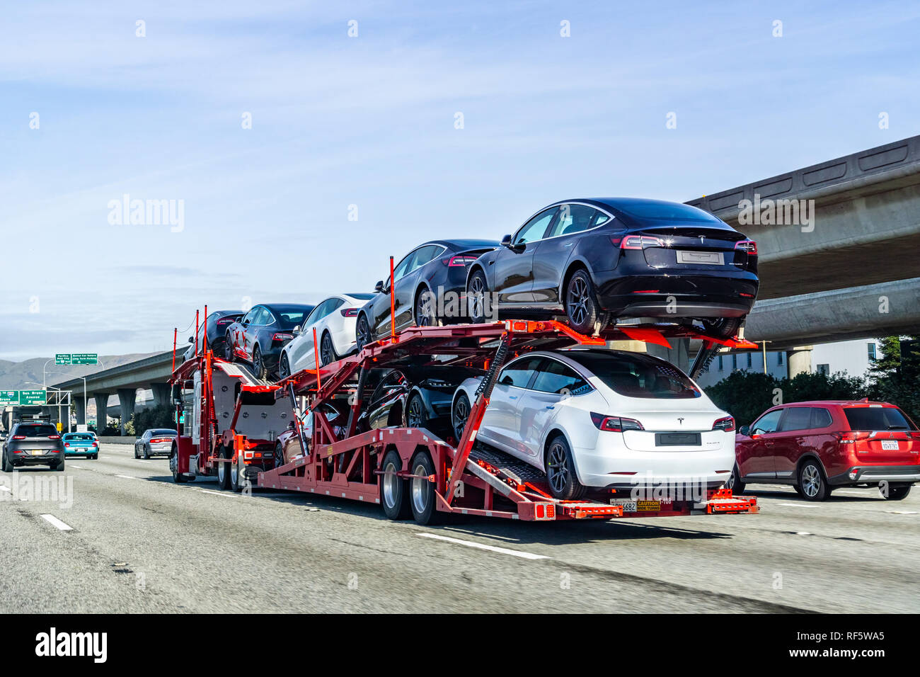 January 19, 2019 San Bruno / CA / USA - Car transporter carries Tesla Model 3 new vehicles along the highway in San Francisco bay area, back view of t Stock Photo