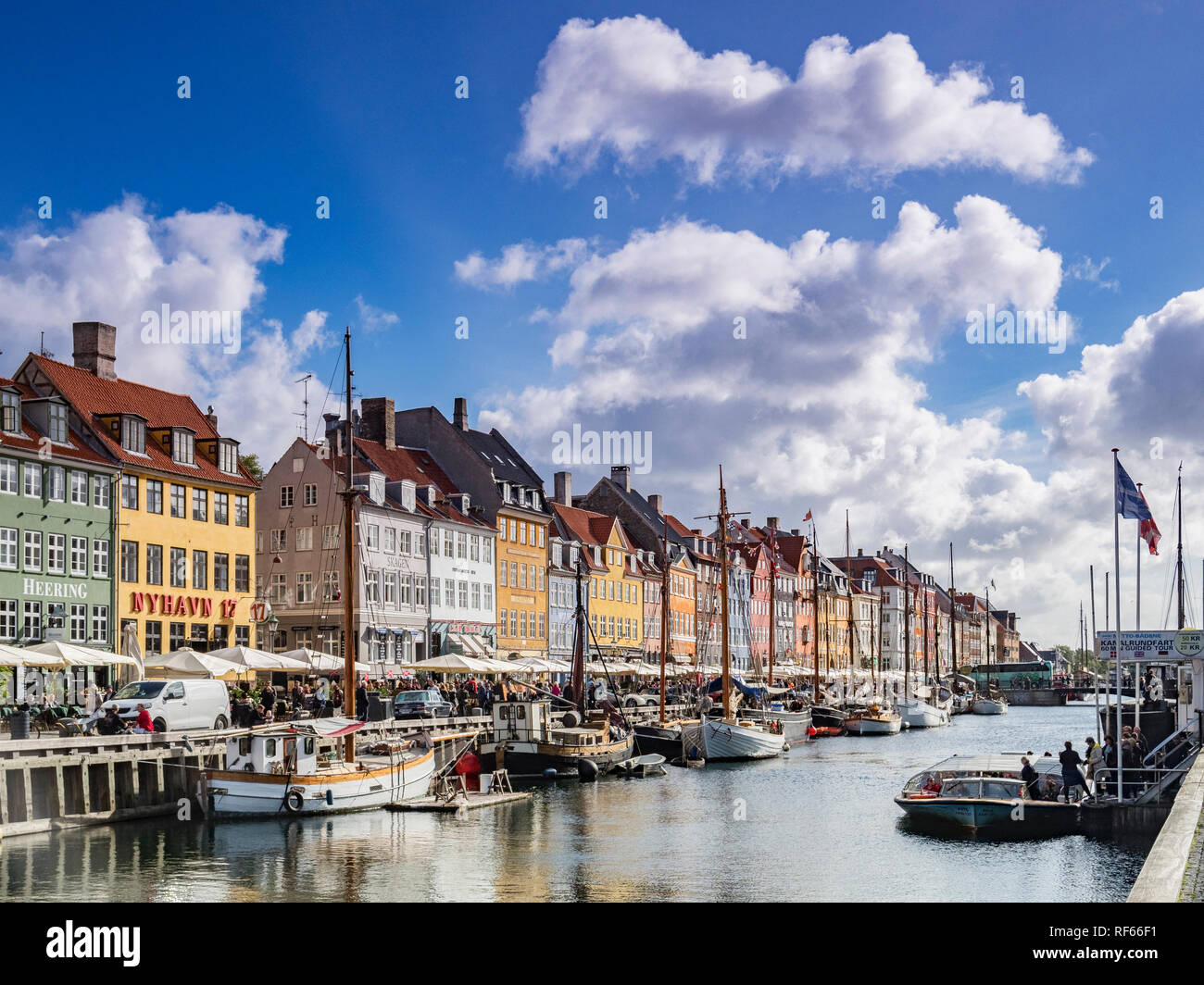 23 September 2018: Copenhagen, Denmark - The canal lined with boats and colourful houses  at Nyhavn on a sunny autumn say with big fluffy white clouds Stock Photo