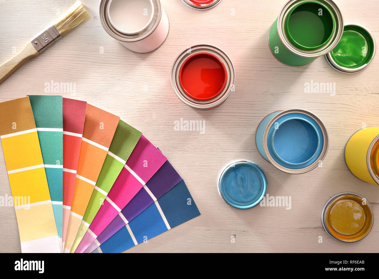 Colorful paint pots open and color palette on white table for renovation of materials. Top view. Horizontal composition. Stock Photo