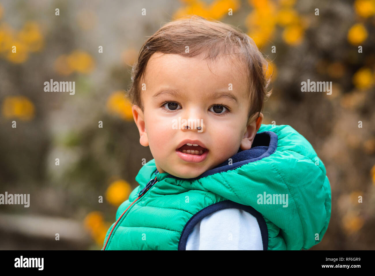 Outdoor portrait of mixed raced toddler in a garden, out of focus marigold flowers in the background. Stock Photo