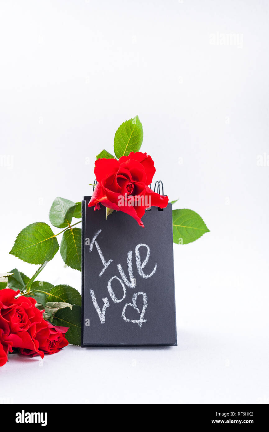 A bouquet of red roses and a letter with the text of love. Gift and flowers on a white background. The concept of lovers day and mother's Stock Photo