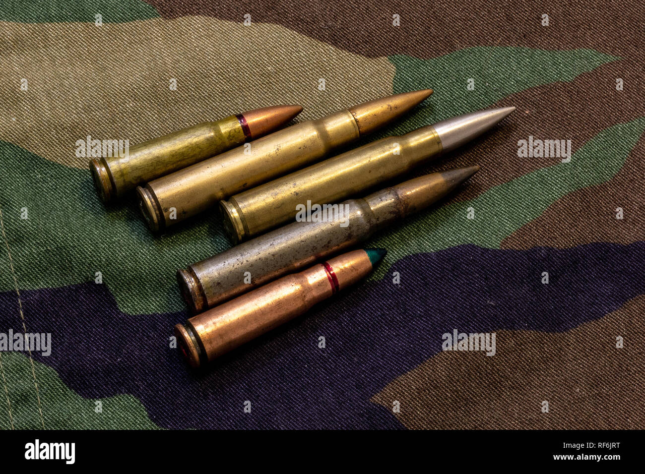 Five rifle bullets on military camouflage coat at background Stock Photo