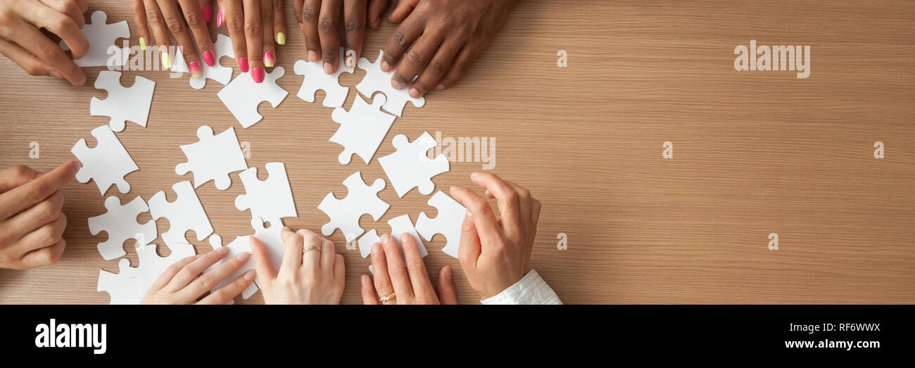Above panoramic view hands of diverse people assembling jigsaw puzzle Stock Photo