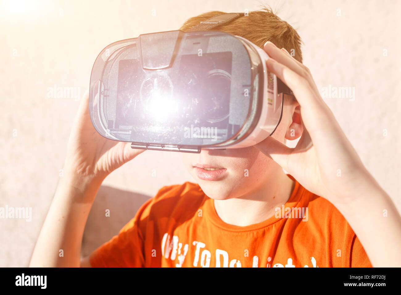 boy in orange t-shirt with VR AR 360 virtual reality glasses cardboard for  mobile phone playing the game. Device for watching movies for travel and en  Stock Photo - Alamy