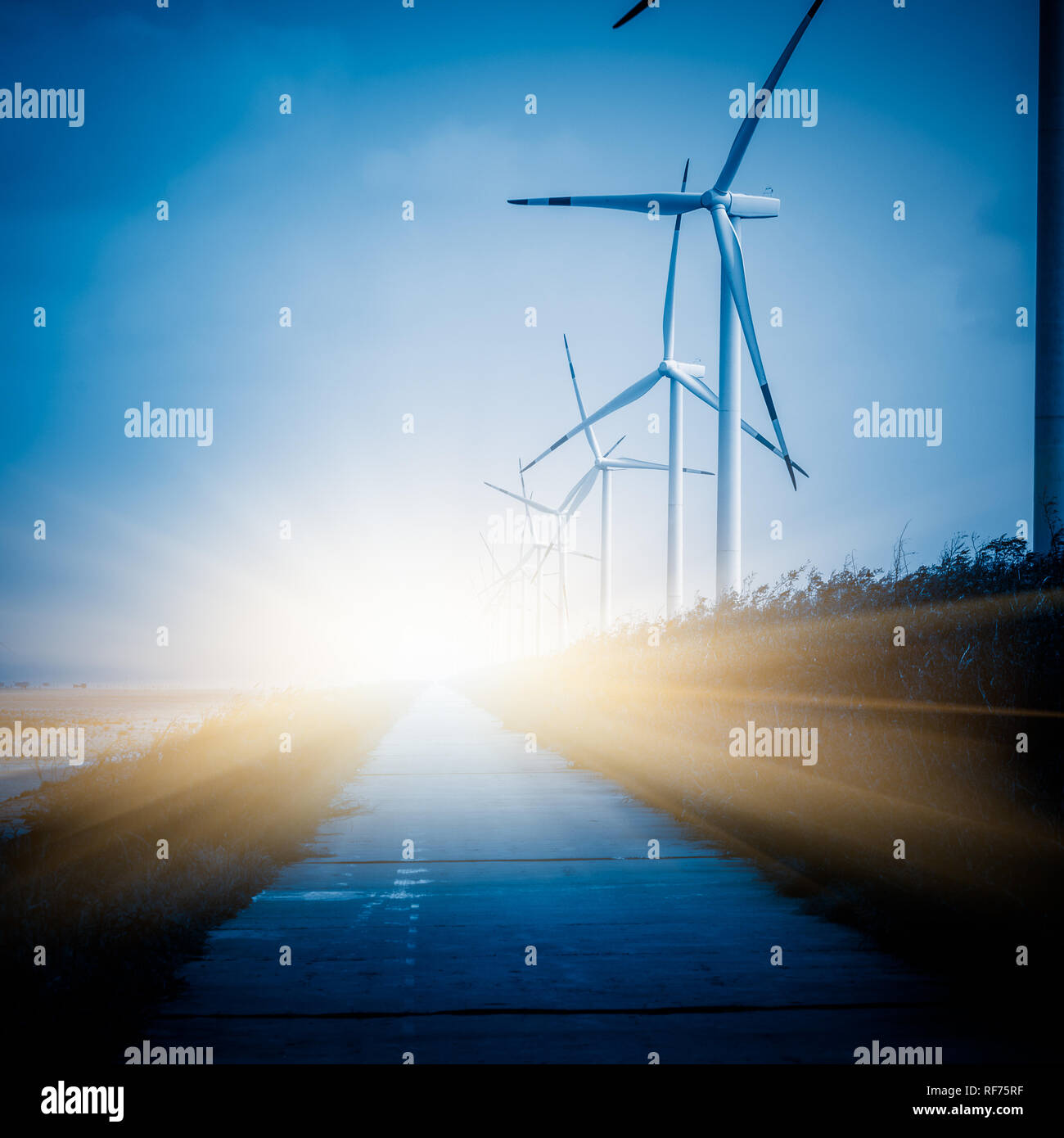 Wind turbines on landscape along empty road against sky Stock Photo - Alamy