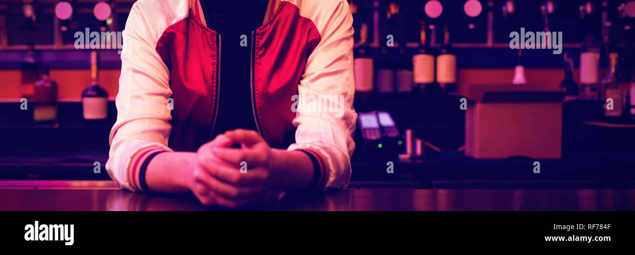 Female bartender standing at bar counter Stock Photo
