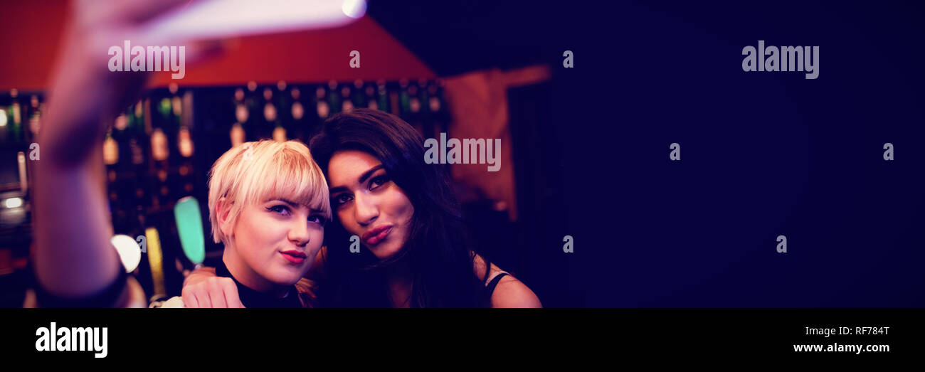 Friends posing while taking selfie in bar Stock Photo