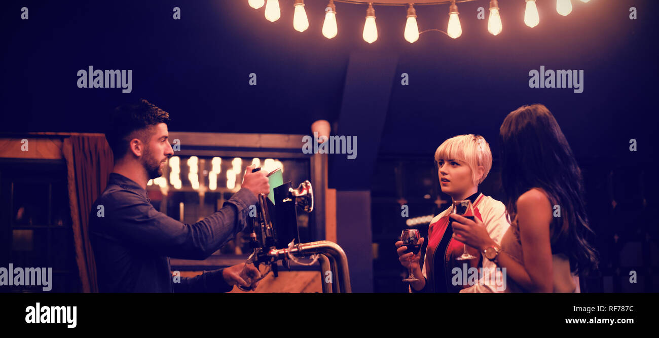 Bartender interacting with beautiful women at counter Stock Photo