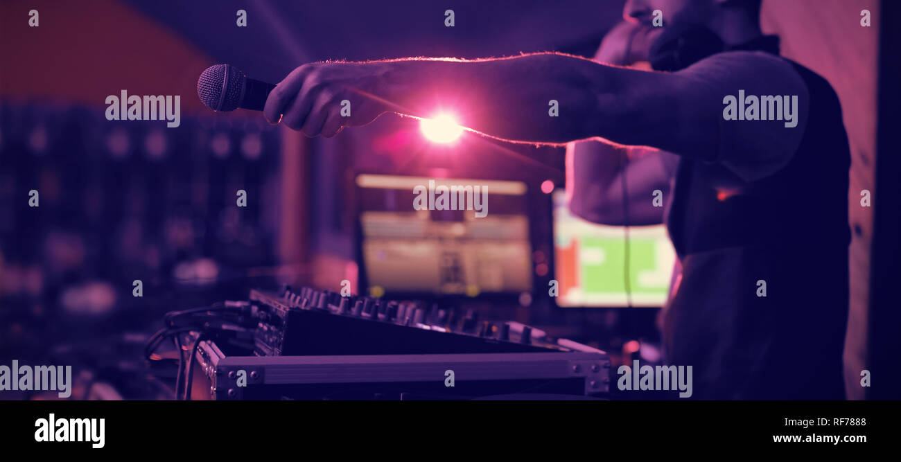 Male dj holding microphone towards the crowd while playing music Stock Photo