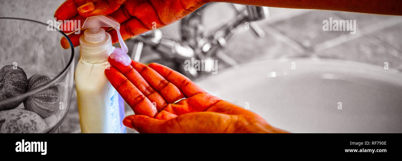 Cropped hands using soap dispenser in bathroom Stock Photo