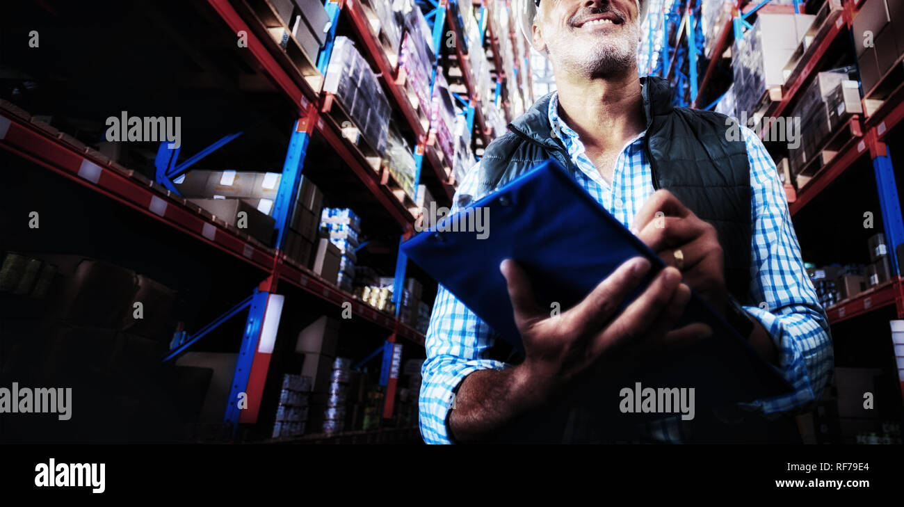 Worker is smiling and holding a clipboard in a warehouse Stock Photo