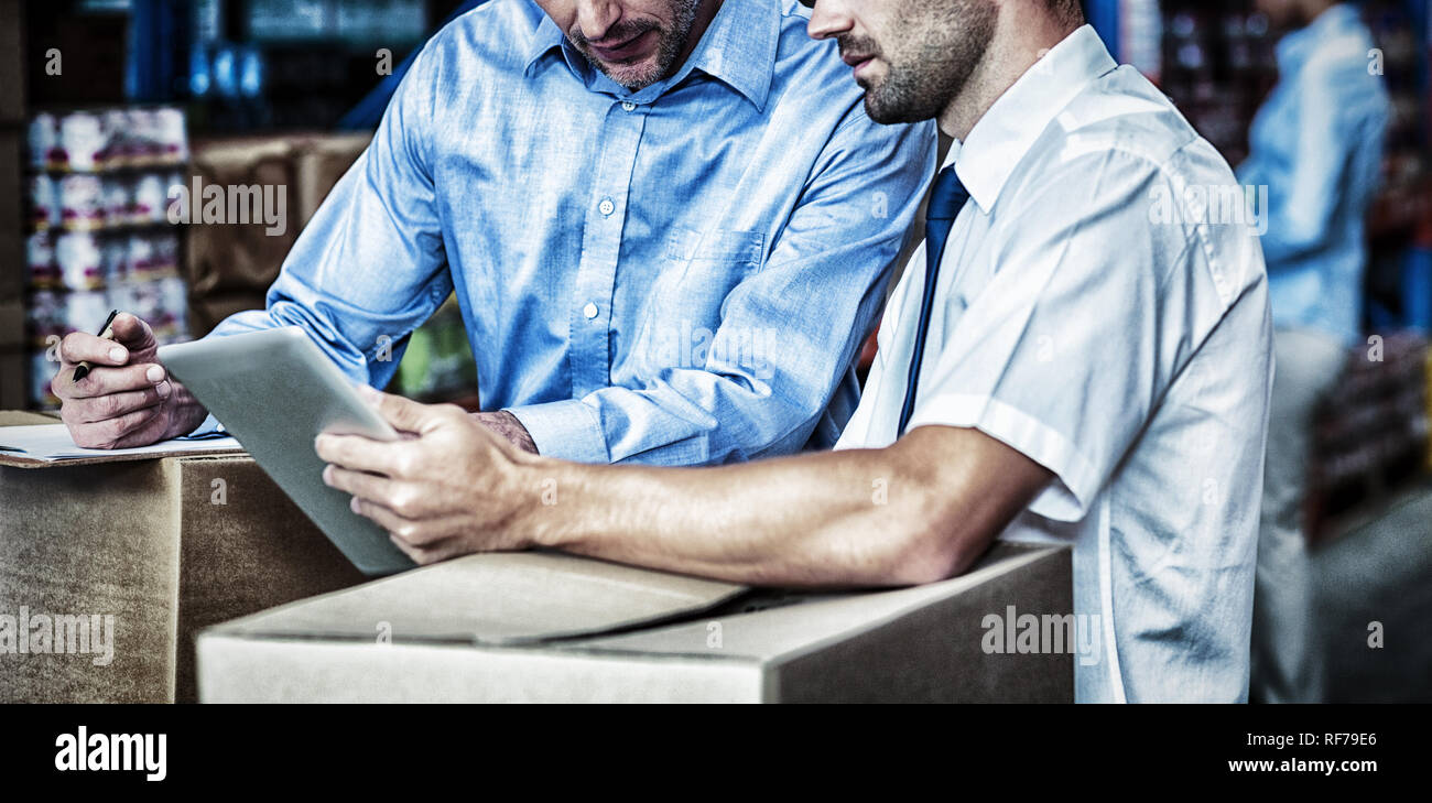 Portrait of managers are working with a tablet in the middle of cardboard boxes Stock Photo