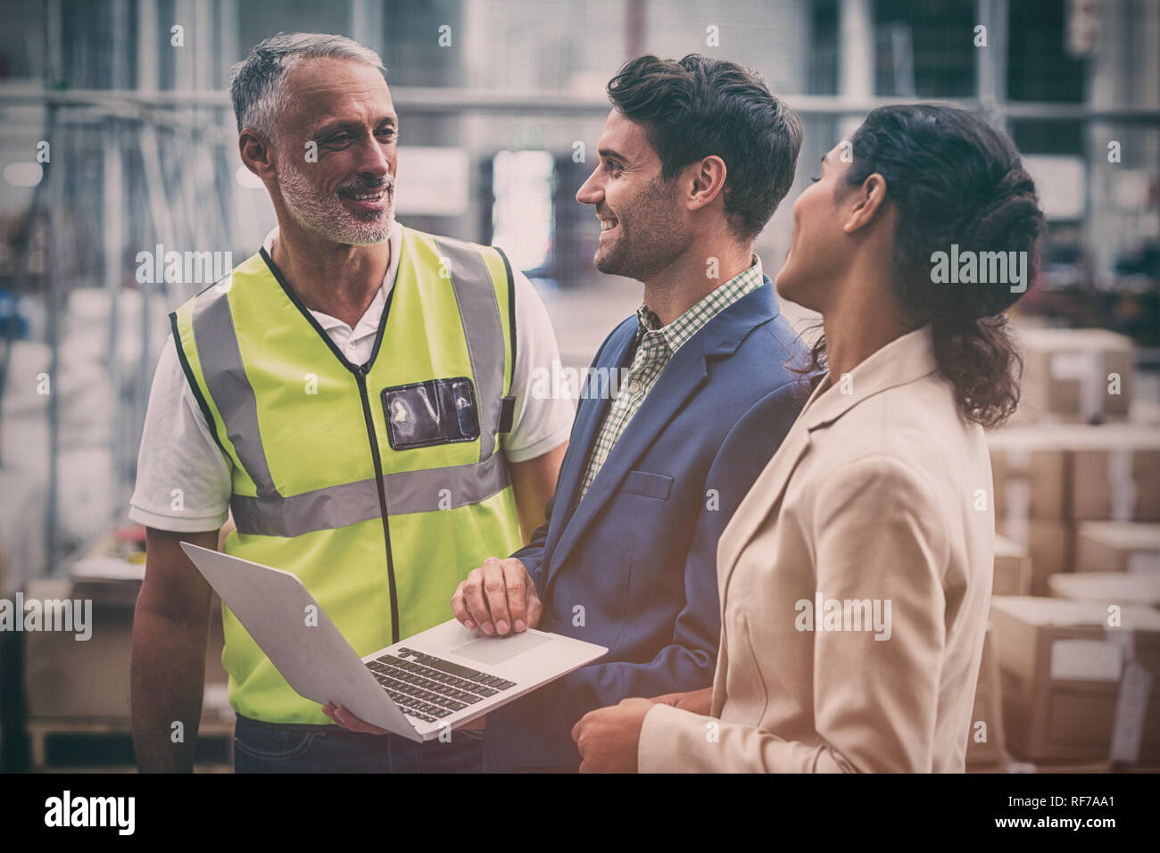 Warehouse managers and worker discussing with laptop Stock Photo