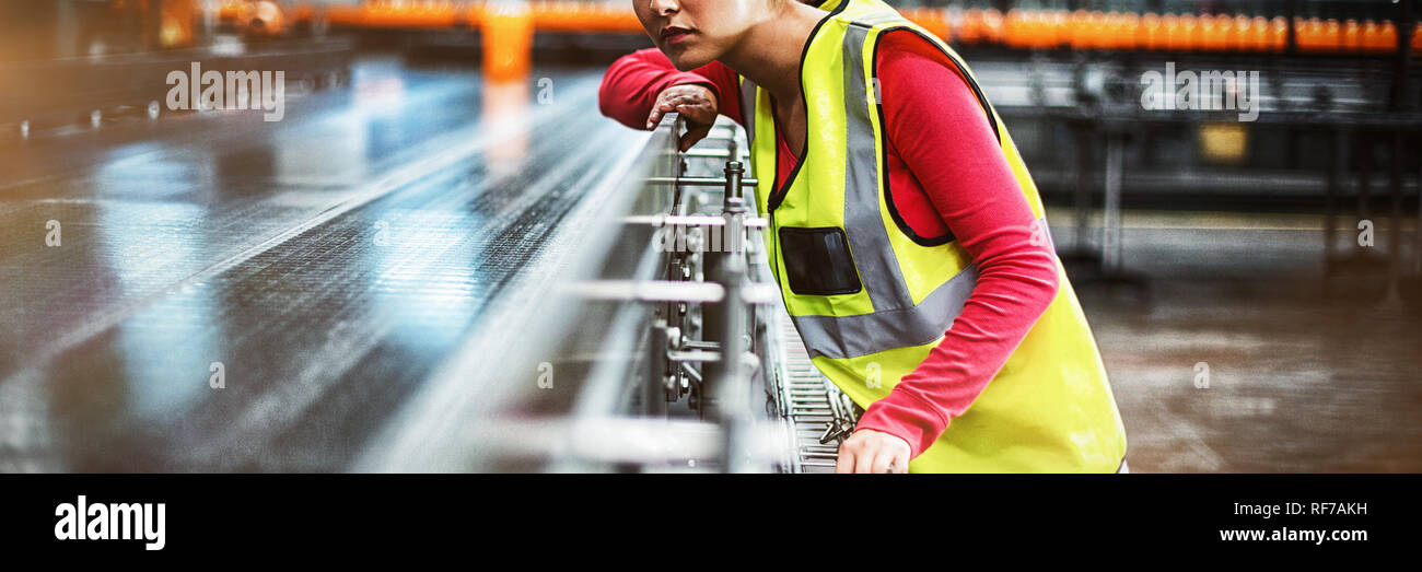 Female factory worker checking conveyor belt Stock Photo