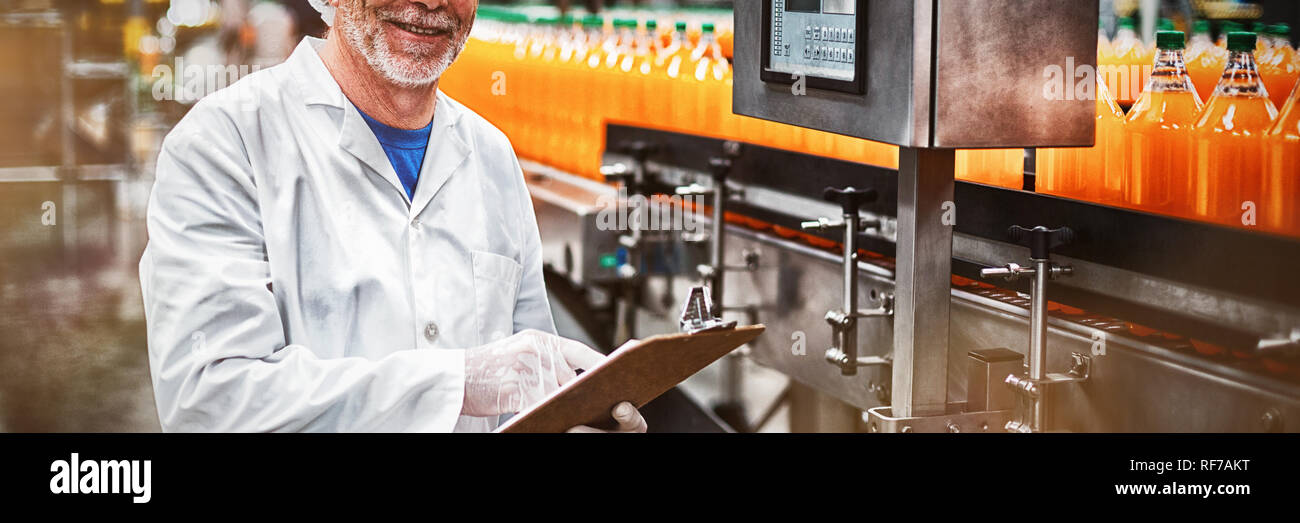 Smiling factory engineer maintaining record on clipboard in factory Stock Photo