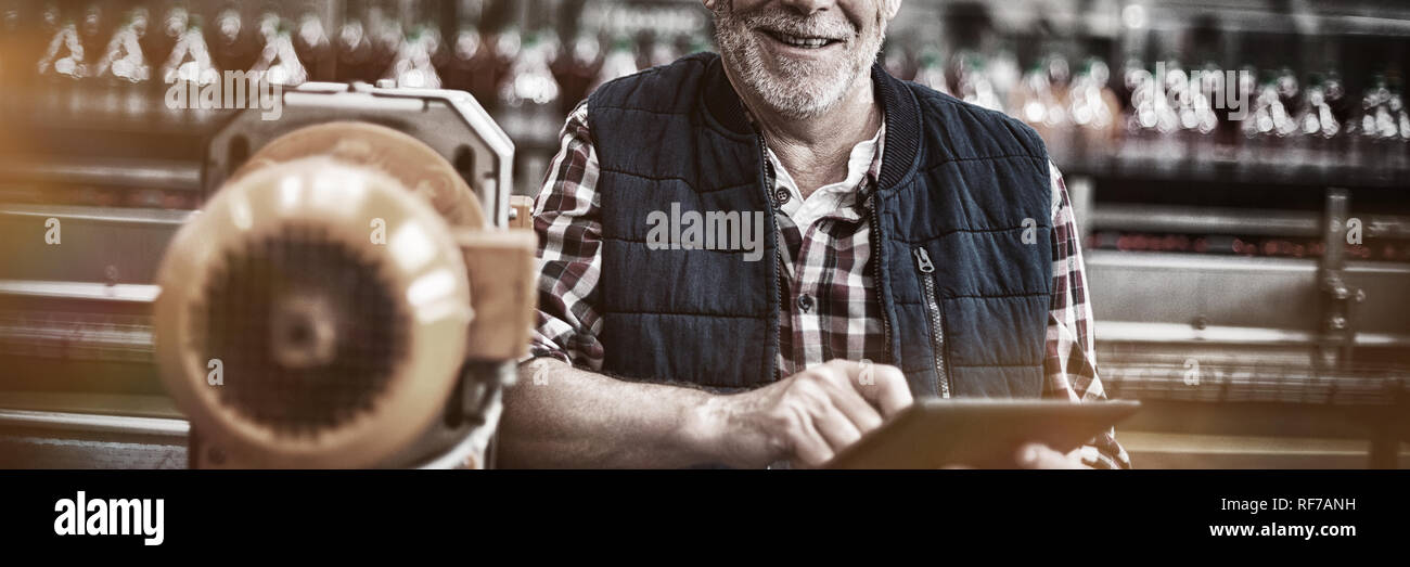 Portrait of smiling factory worker standing with a digital tablet in the factory Stock Photo