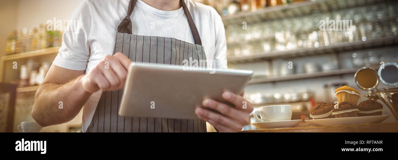 Happy barista using digital tablet at cafe Stock Photo
