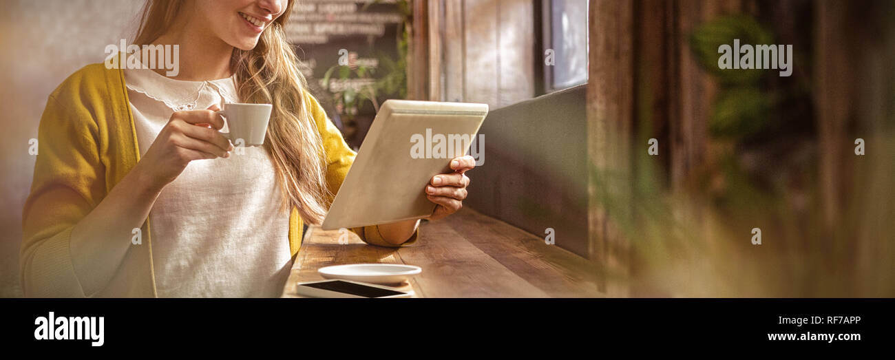 Smiling woman drinking coffee and using tablet Stock Photo