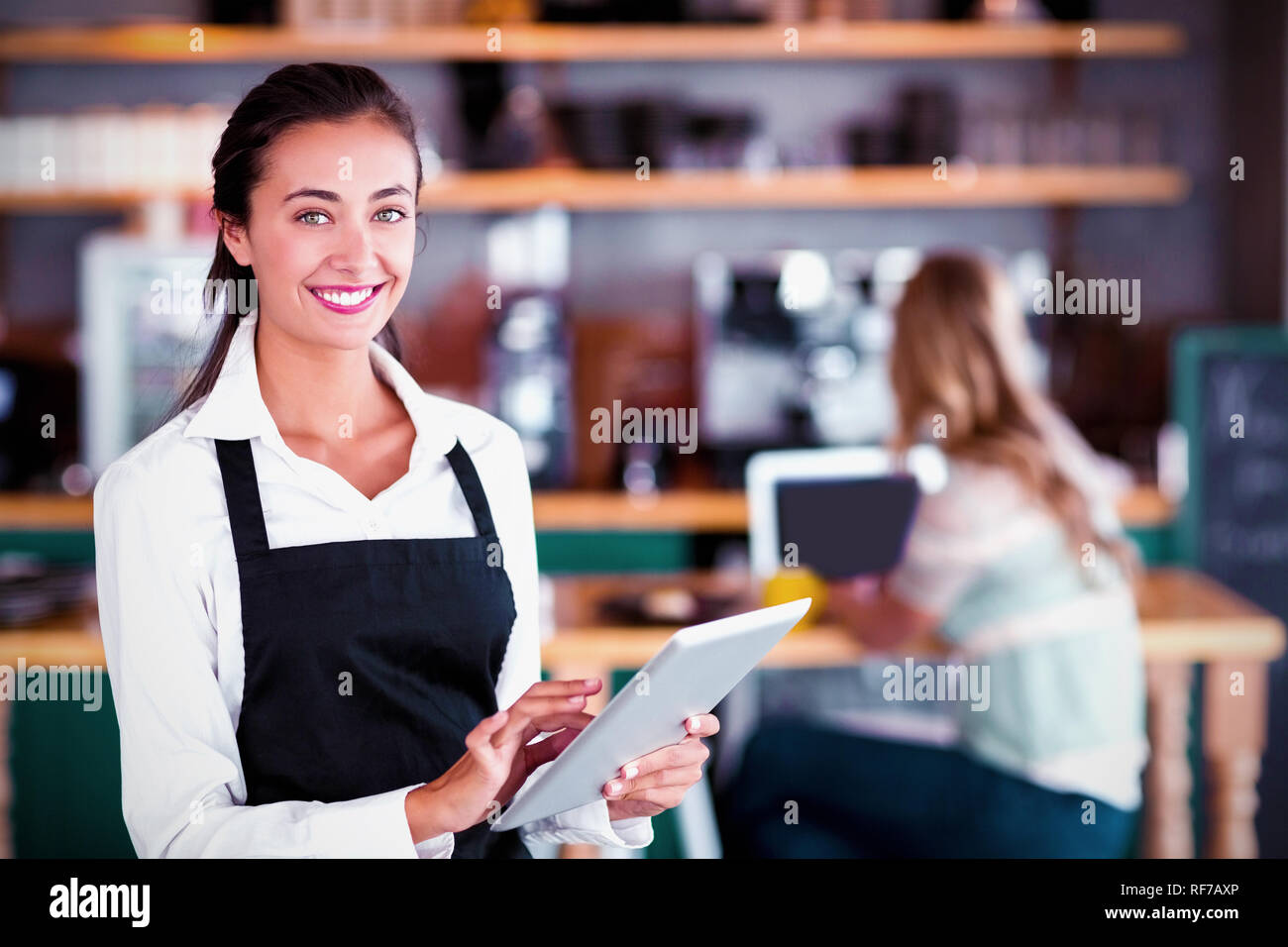Portrait of smiling waitress using digital tablet Stock Photo
