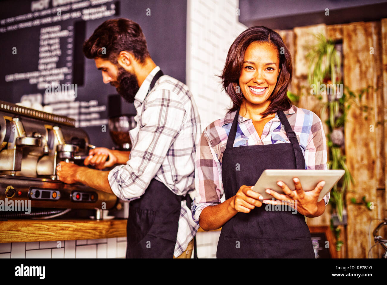 Waitress using a tablet computer and waiter with coffee machine Stock Photo