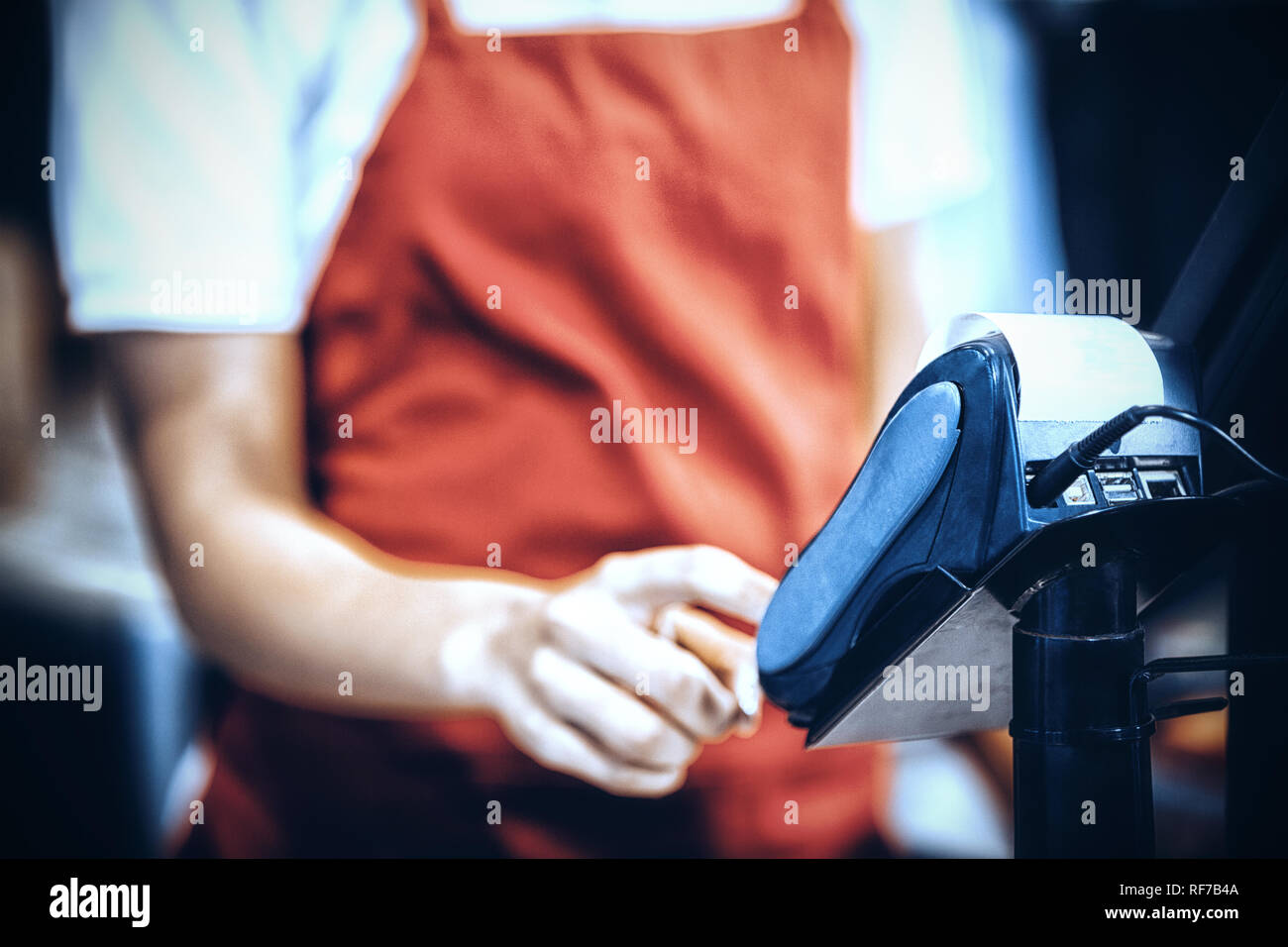 Female staff using credit card terminal at cash counter Stock Photo