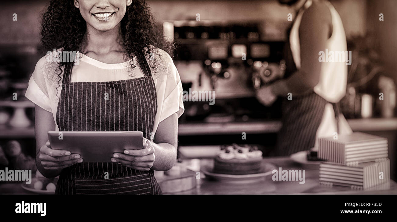 Smiling waitress using digital tablet at counter in cafÃƒÂ© Stock Photo
