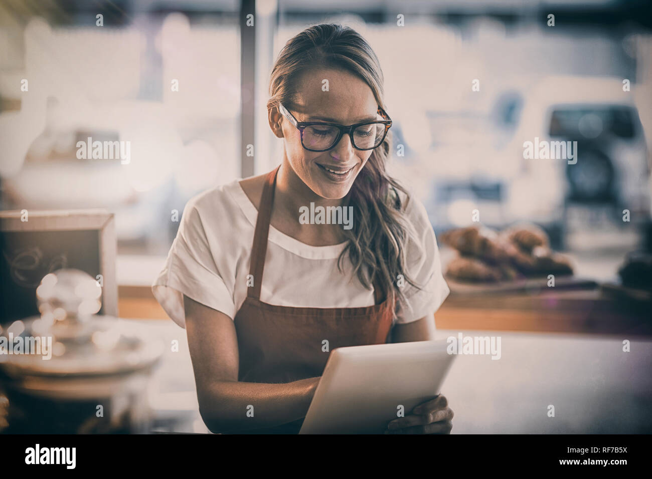 Waitress sitting at table and using digital tablet in cafe Stock Photo