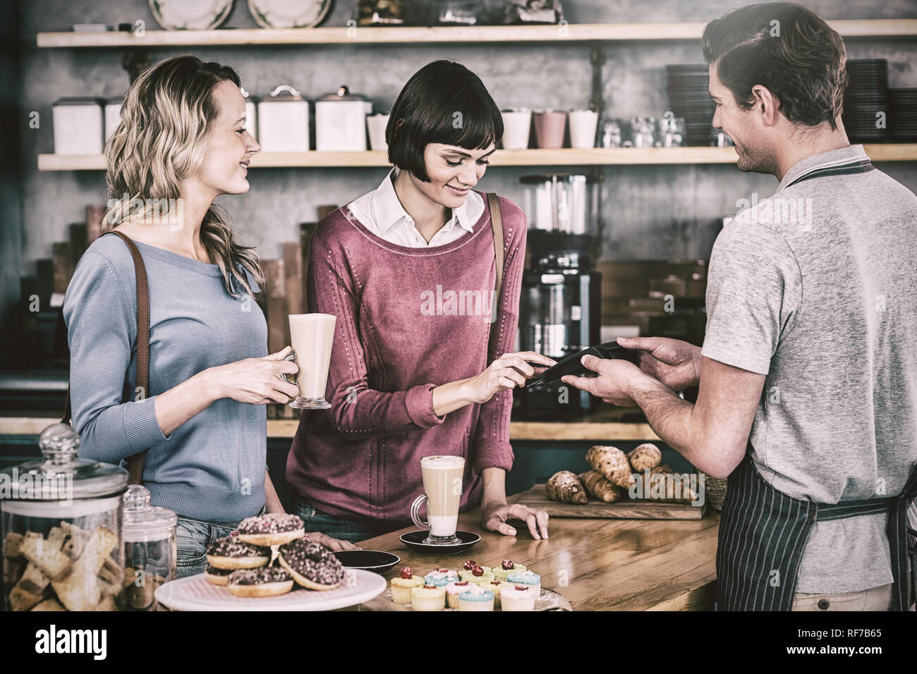 Customer making payment through payment terminal at counter Stock Photo ...