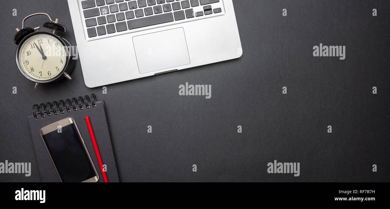 Time management concept. Computer laptop and alarm clock on black color office desk, banner, top view, copy space Stock Photo