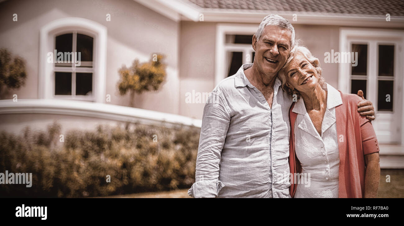 Senior couple with arms around standing in yard Stock Photo