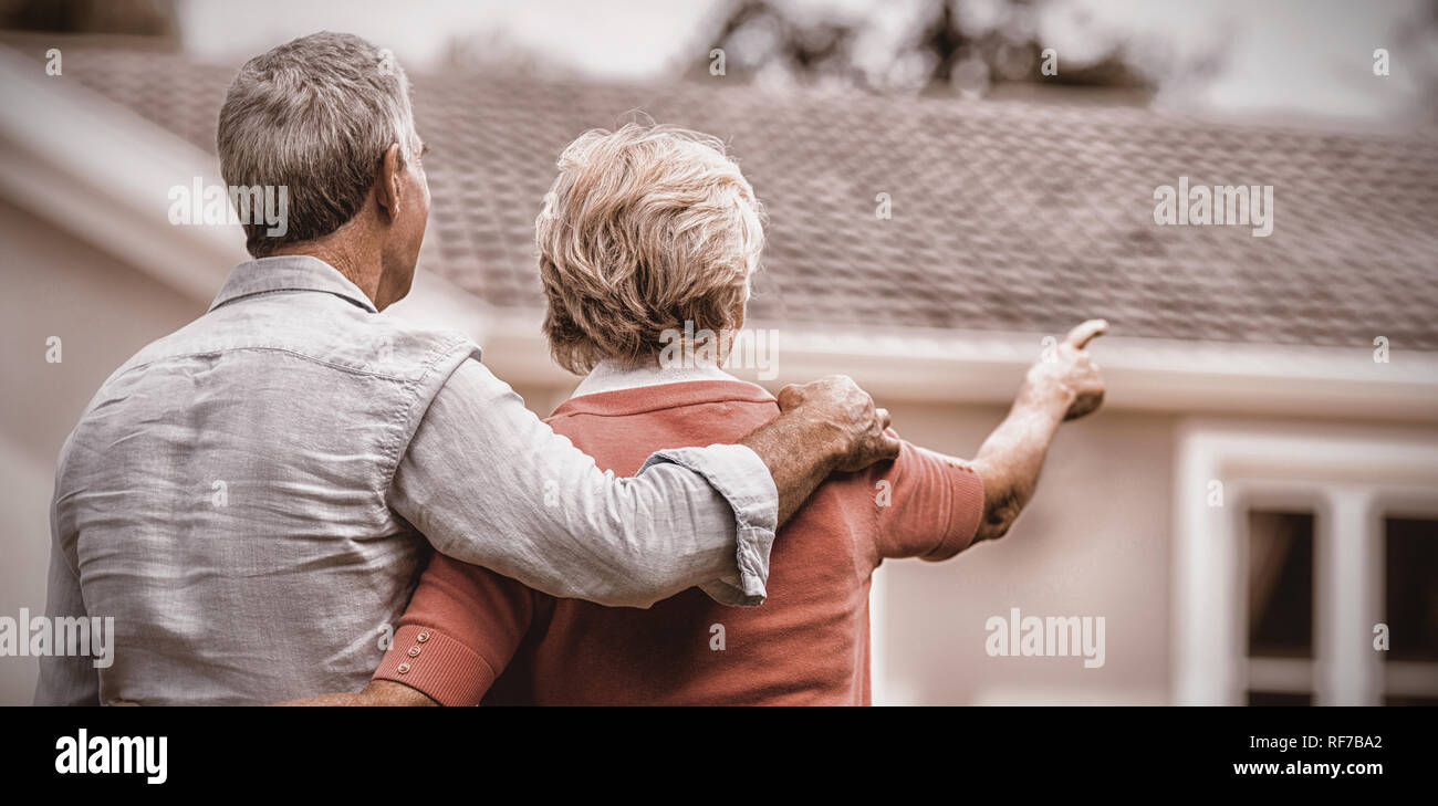 Senior couple looking at house while standing ih yard Stock Photo