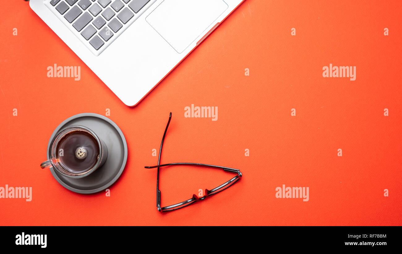 Modern workspace. Computer laptop and mobile phone on orange color