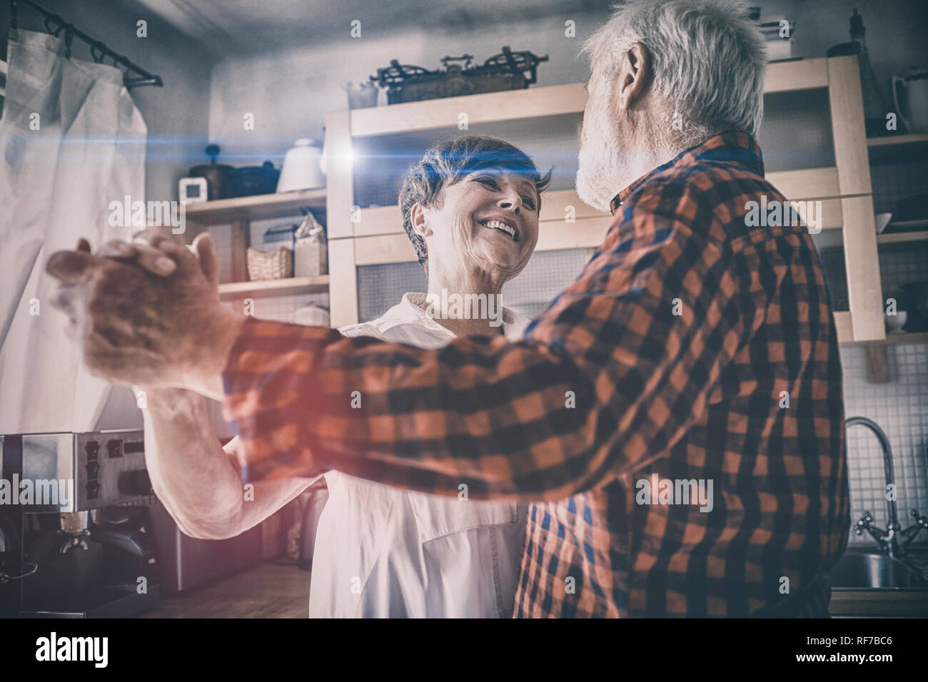 Senior couple dancing together in kitchen Stock Photo