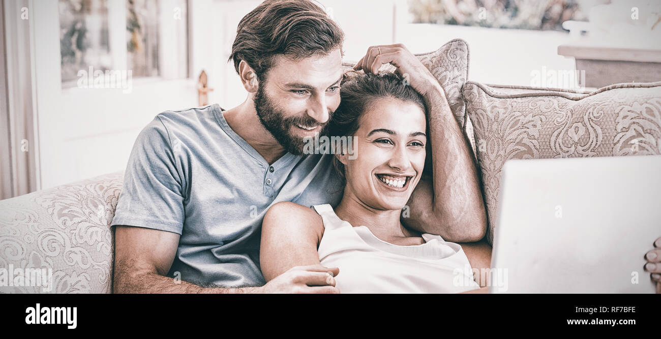 Couple sitting on sofa and using laptop Stock Photo