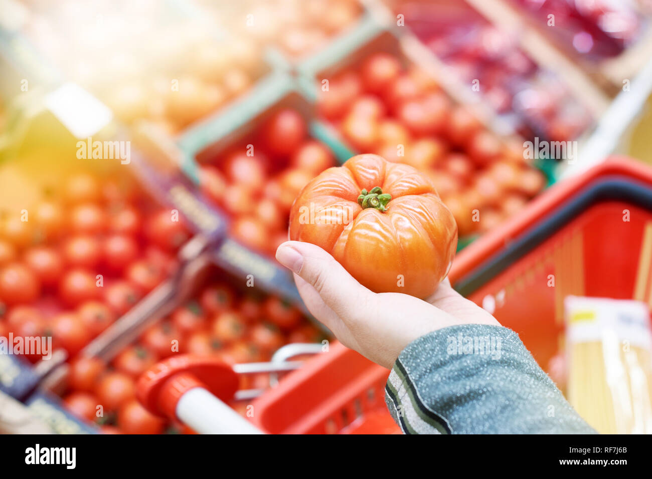 Tomato in the hand of the buyer at the grocery store Stock Photo