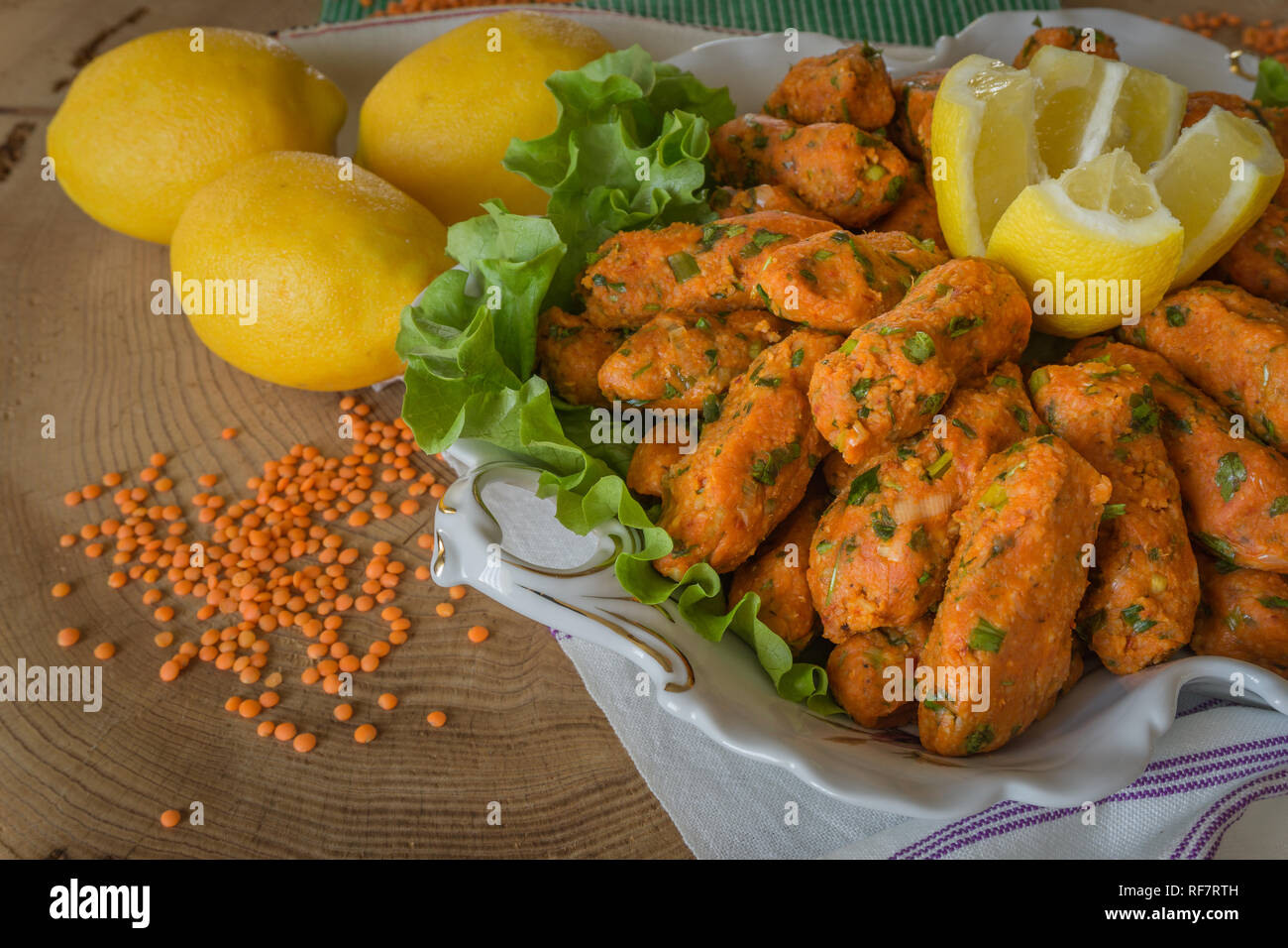 Red lentil balls served with lemons. Traditional turkish food. Red lentil balls serving with lemons on the plate. Stock Photo