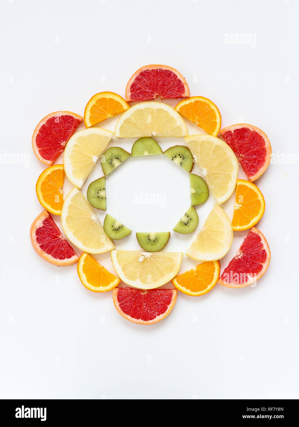 Creative pattern of sliced fruits - kiwi, orange and grapefruits - arranged in a circle. Flat lay with copy space Stock Photo