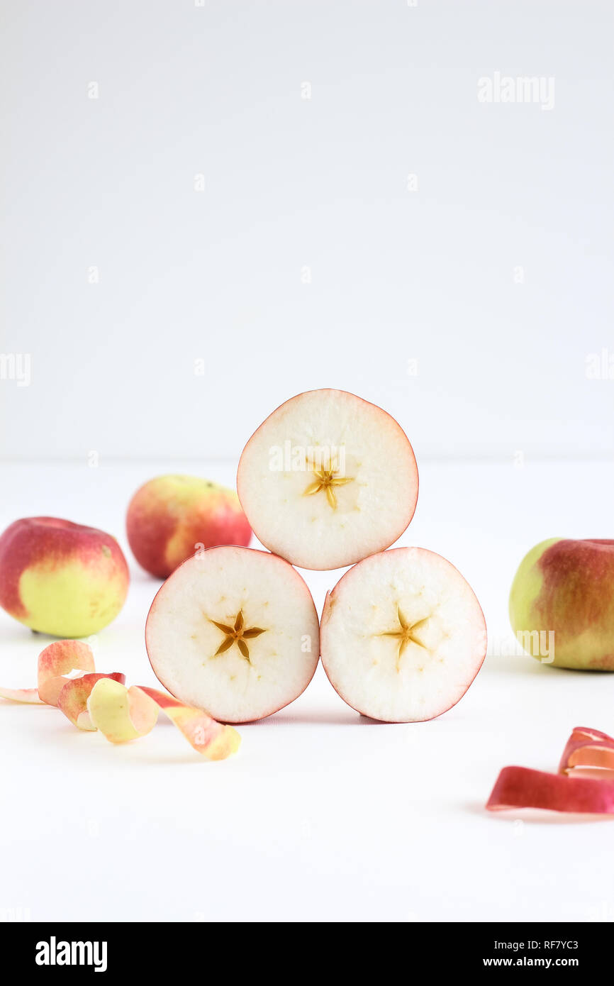 Stacked sliced pieces of apple and whole apples in the background Stock Photo