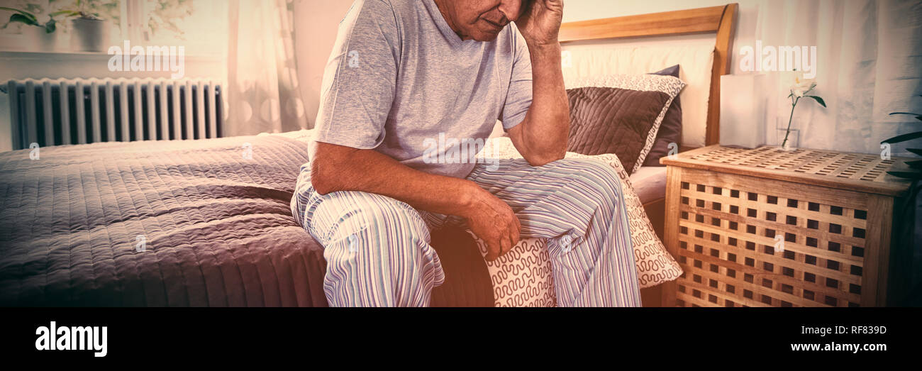 Frustrated senior man sitting on bed Stock Photo