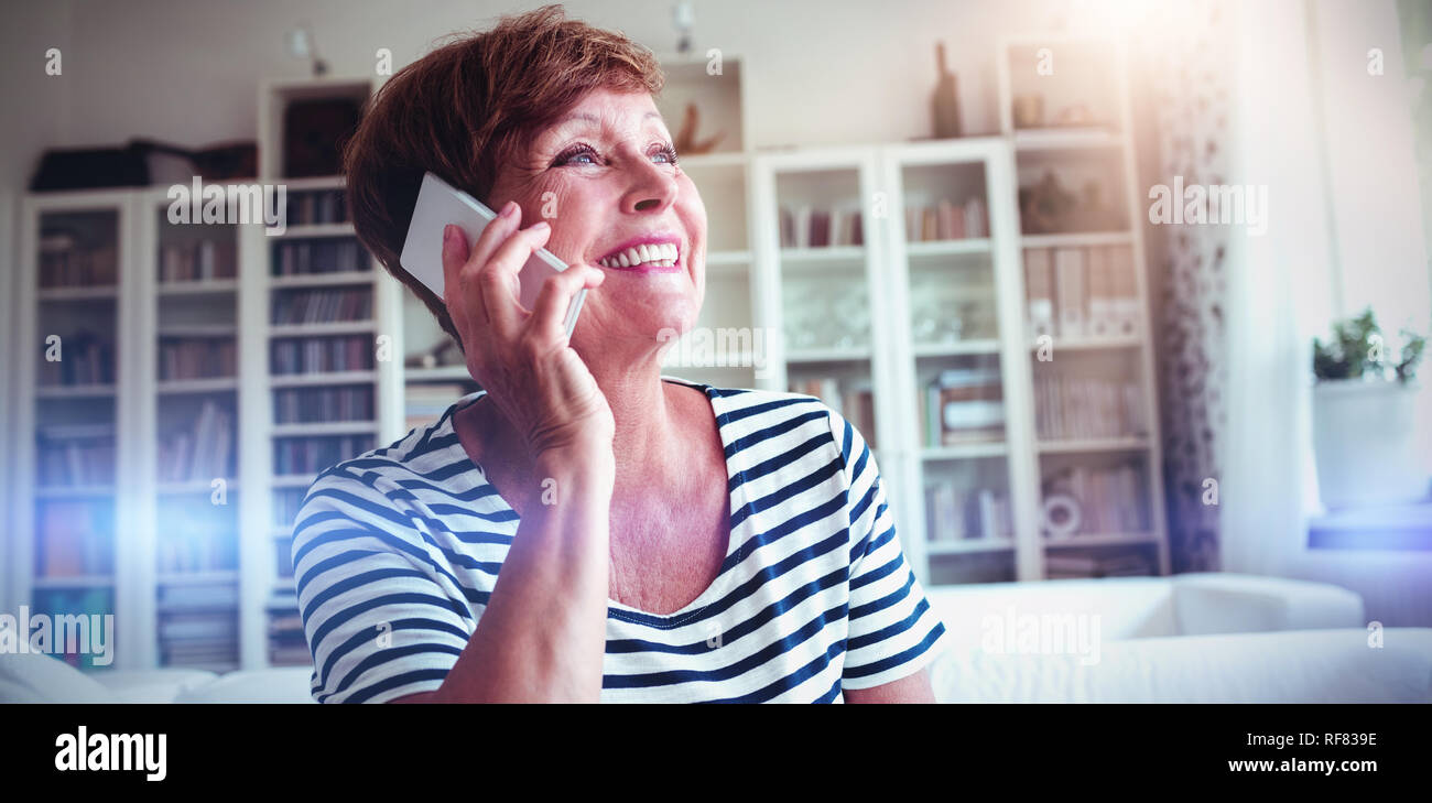 Senior woman talking on mobile phone in living room Stock Photo