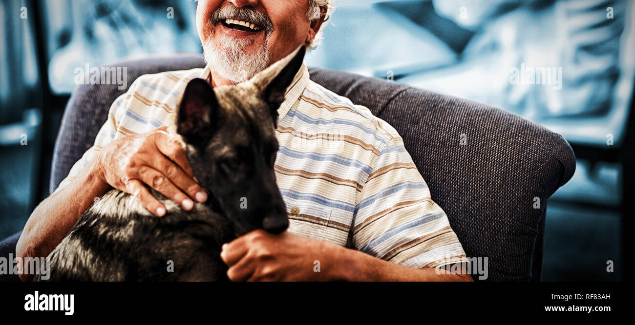 Portrait of smiling senior man sitting with puppy on chair Stock Photo