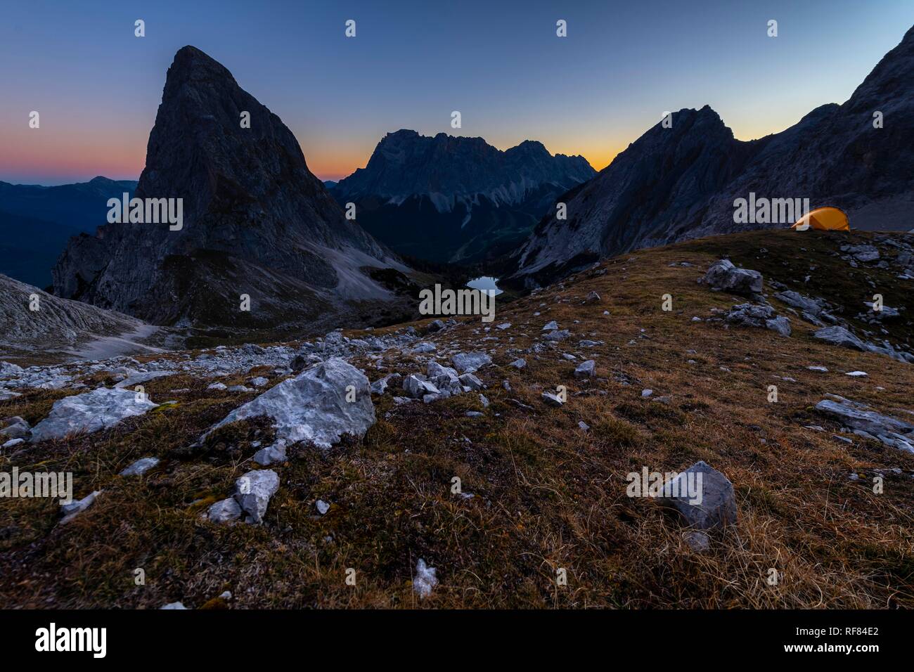 Peak of Sonnenspitze with tent and Zugspitze in the background at blue hour, Ehrwald, Außerfern, Tyrol, Austria Stock Photo