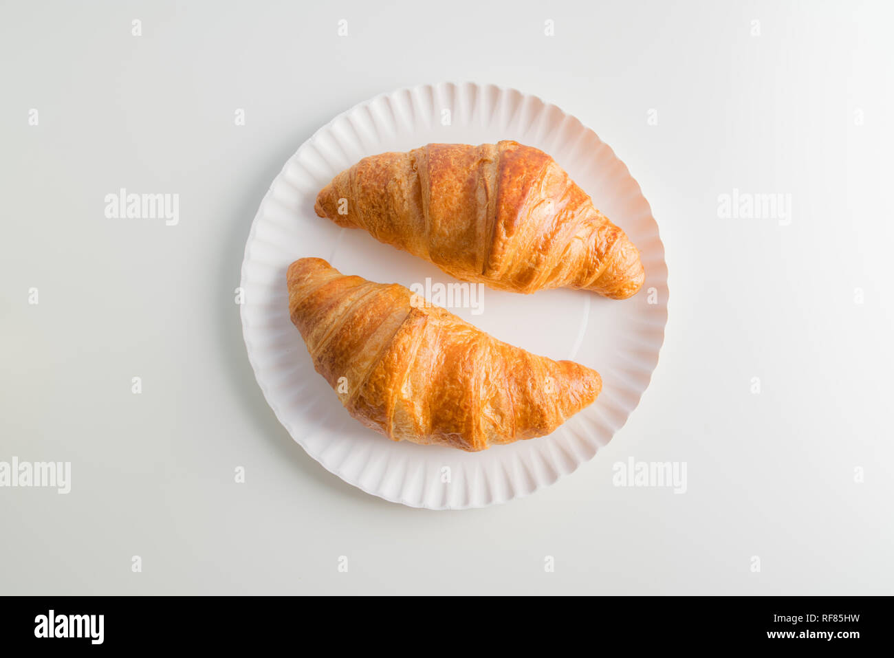Two plain croissant on the plate, white table background Stock Photo