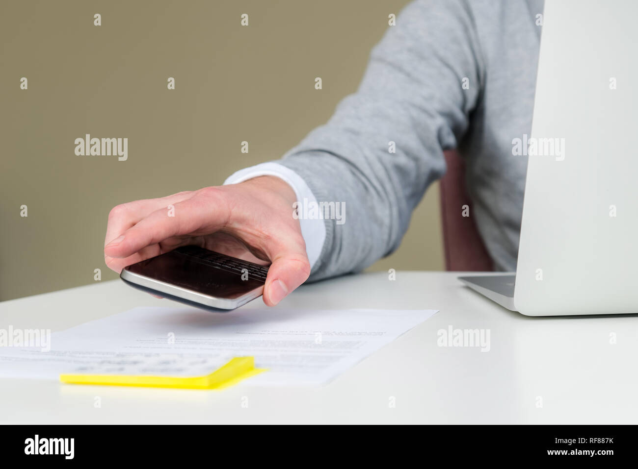 Close up of young business student man using smart phone at workplace. Closeup of hand of man using smartphone at office desk. Men reading a message p Stock Photo