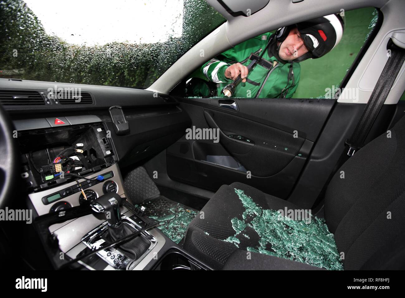 Police officer inspecting a car broken into by thieves who have stolen a radio and navigation system, Essen Stock Photo